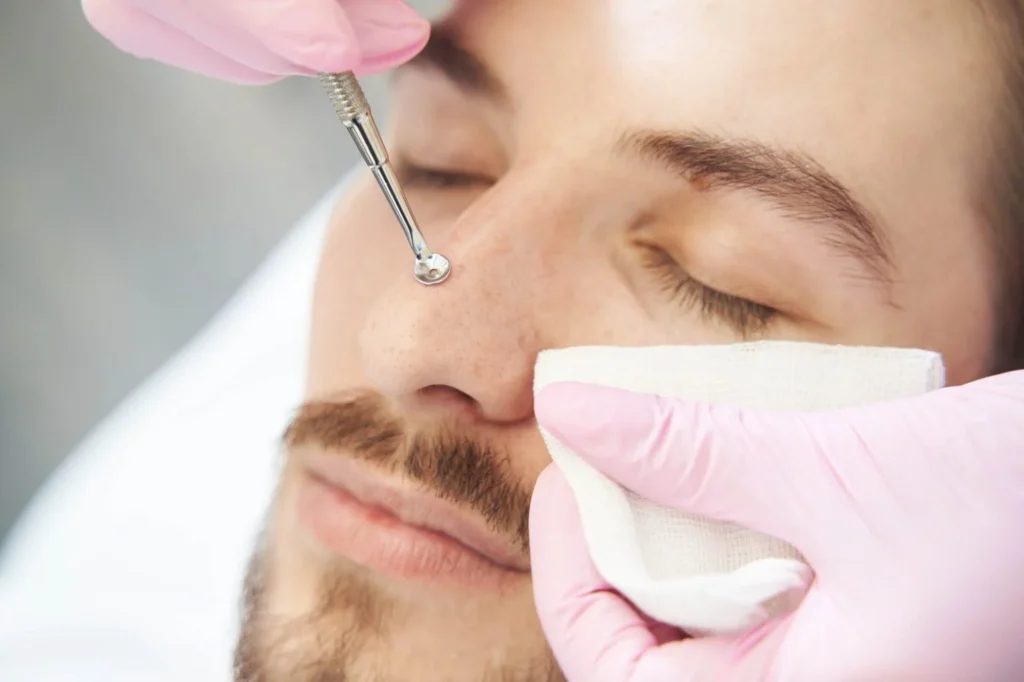 Client enjoys a relaxing facial at Anchorage Med Spa; professional gently uses comedone extractor, wearing pink gloves and holding white cloth.