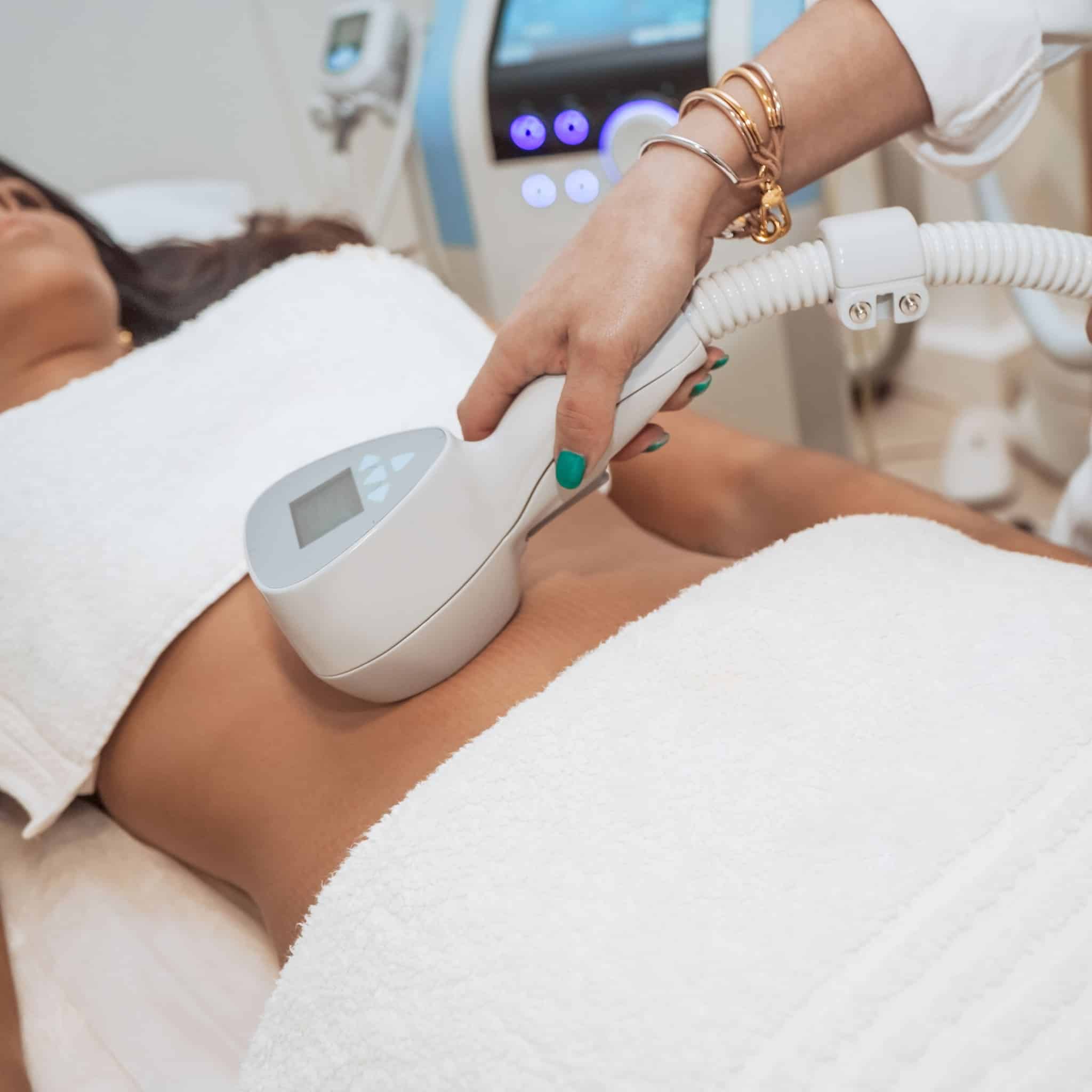 Person receiving body contouring treatment with a handheld device on abdomen at a medical spa in Anchorage.